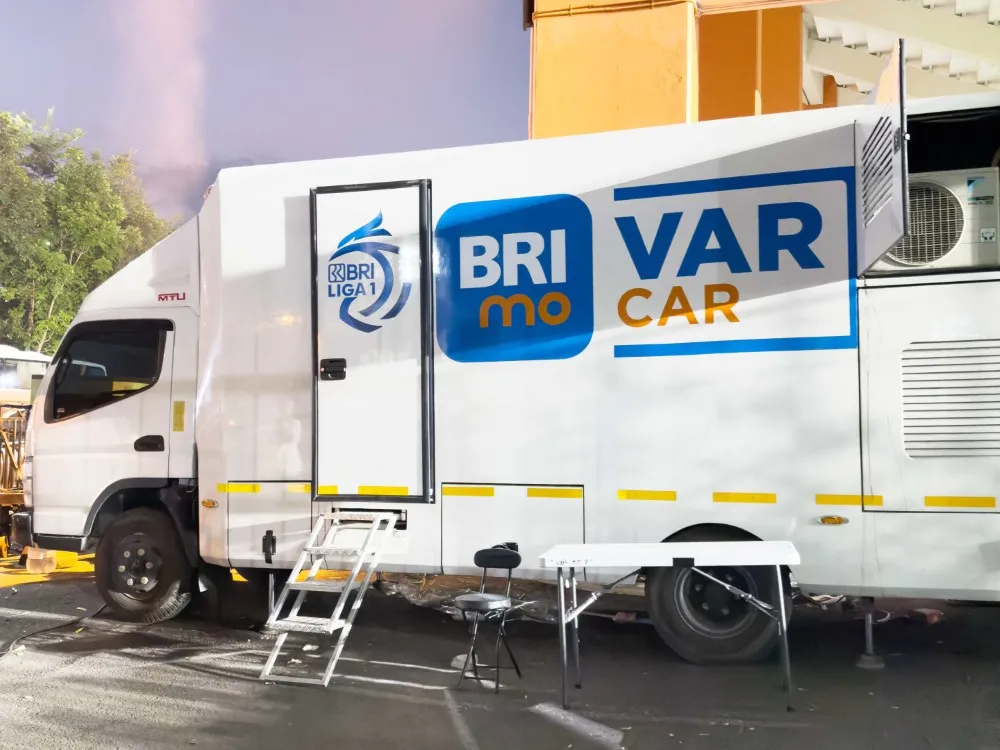 Bandung, Indonesia – PT Krama Yudha Tiga Berlian Motors (KTB), distributor resmi kendaraan niaga Mitsubishi Fuso Truck and Bus Corporation (MTFBC) di Indonesia, merasa bangga karena Canter FE 84 G dioperasikan sebagai Video Assistant Referee Mobile (VAR Mobile) untuk mengawasi jalannya pertandingan pembuka Liga 1 Musim 2024 / 2025 antara PERSIB Bandung melawan PSBS Biak di Stadion Si Jalak Harupat, Bandung pada 9 Agustus 2024 lalu. VAR biasanya ditempatkan di dalam stadion pertandingan, namun di Indonesia, jumlah stadion yang memadai untuk teknologi VAR ini sangat terbatas. Hal ini mendorong Liga Indonesia Baru (LIB) mencari solusi untuk kualitas pertandingan sepak bola yang lebih baik dengan mencetuskan ide VAR Mobile. VAR Mobile menempatkan sistem dan teknologi VAR kedalam sebuah truk yang dapat dimobilisasi ke stadion-stadion di seluruh Indonesia. LIB memilih chassis Canter FE 84 G sebagai truk yang ideal dan memenuhi standar untuk dijadikan ruang VAR karena varian ini memiliki dimensi yang lebar sehingga memberikan kapasitas ruang yang besar. Canter FE 84 G menggendong mesin 4V21-2AT1 dengan tenaga 136 PS dan torsi maksimal 43kgm yang didapat pada rentangan rpm sebesar 1.500 – 2.500. Saat ditemui dalam pertandingan PERSIB Bandung vs PSBS Biak yang berlangsung, Ahmad Ikrom Maulana, Supervisor Football Technology & Innovation PT Liga Indonesia Baru mengatakan, “ketika adanya perpindahan lokasi di lapangan, dengan adanya Truk VAR ini, kita bisa memindahkan alat-alat VAR kita lebih mudah. Jadi kita memilih mobil yang cukup untuk memasukkan alat kita dan memang ada standar ukuran minimalnya untuk membuat ruangan VAR itu,” ujarnya. Pada kesempatan yang sama, Manager Media & Communication PT Liga Indonesia Baru, Hanif Marjuni menambahkan, pembuatan untuk satu unitnya memakan waktu sekitar enam bulan. Adapun saat ini LIB memiliki 12 armada yang tersebar di beberapa daerah untuk menjangkau stadion-stadion yang ada di Indonesia. Lebih lanjut, Hanif mengatakan bahwa mereka harus mencari kendaraan yang tangguh di segala medan, karena mobilitas truk VAR akan bergerak ke daerah lainnya di seluruh Indonesia. “Pertimbangan kita adalah pilih yang tangguh, karena mobil ini akan rolling dan berpindah ke seluruh Indonesia, jadi itu bagian dari pertimbangan kami, bagaimana bisa menyediakan satu mobil yang semuanya mumpuni untuk alat-alat VAR.” Dipilihnya FUSO Canter FE 84 G sebagai inovasi VAR pertama di Indonesia tentu menjadi sebuah kebanggaaan bagi Mitsubishi FUSO. Sudaryanto, General Manager of Business Communication PT Krama Yudha Tiga Berlian Motors mengatakan bahwa produk Canter sudah terbukti ketangguhannya dan selalu menjadi favorit masyarakat Indonesia dengan dominasi penjualan mencapai 52,9%. “kehadiran truk VAR ini tidak hanya merupakan bentuk dukungan kami terhadap sepak bola Indonesia, tetapi juga menjadi pembuktian bahwa Mitsubishi Fuso dapat digunakan untuk berbagai kebutuhan bisnis dan lembaga, di berbagai industri,” tutup Sudaryanto.